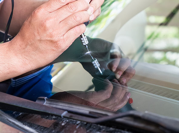 Glazier using tools repairing to fix crack windshield